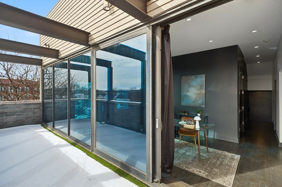 Rooftop area with glass sliding doors leading to an indoor space.