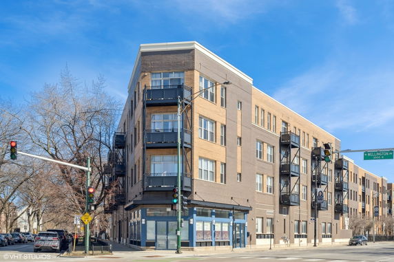 Front view of a multi-story building with balconies on a street corner.