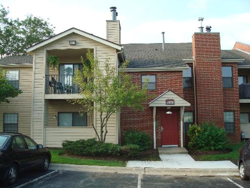 Front view of a two-story residential building with a red brick facade and a pitched roof.