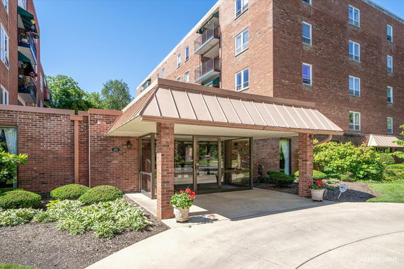 Front view of a multi-story brick building with a glass entrance and balconies.