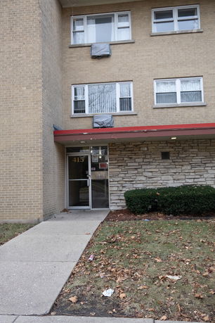 Front view of a multi-story brick apartment building with an entrance.
