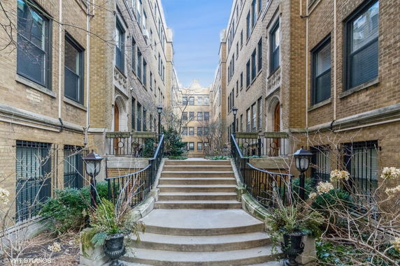 Front view of a multi-story brick apartment building with central courtyard.
