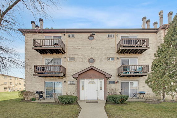 Front view of a three-story apartment building with balconies and a central entrance.