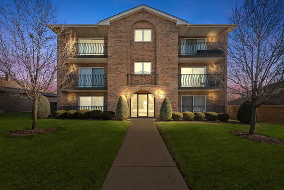 Front view of a multi-story brick apartment building with balconies.
