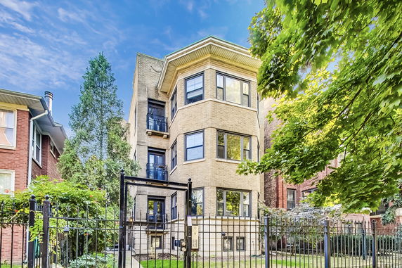 Front view of a multi-story residential building with beige brick exterior.