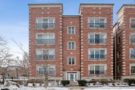 Front view of a multi-story brick apartment building with balconies.