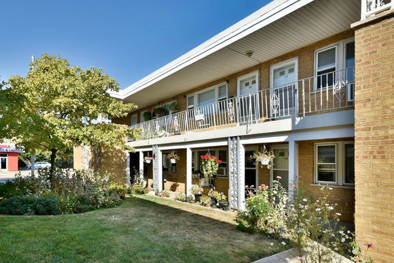 Front view of a two-story brick apartment building with balconies.