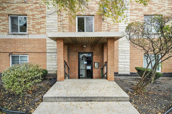 Front view of a brick apartment building entrance with stairs.