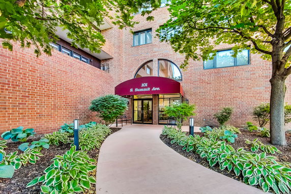 Brick building with arched entrance and red awning.