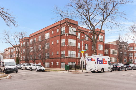 Front view of a multi-story brick apartment building on a street corner.