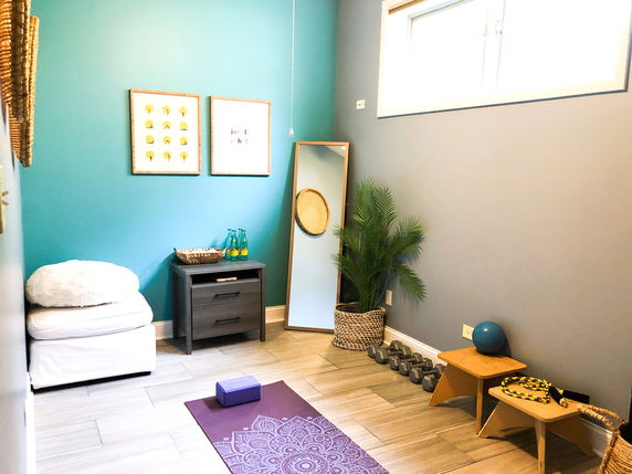 Room with yoga mat, exercise ball, dumbbells, and a mirror.