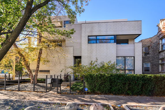 Front view of a multi-story modern house with large windows and a minimalistic design.