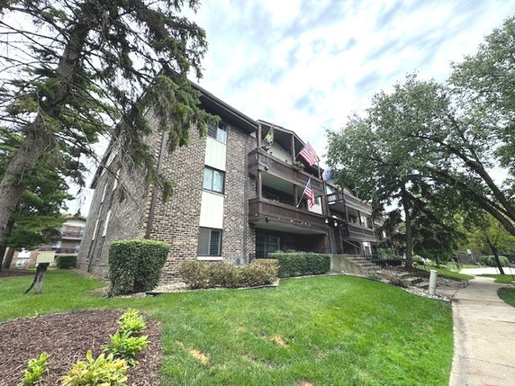 Front view of a multi-story brick building with balconies and flags.