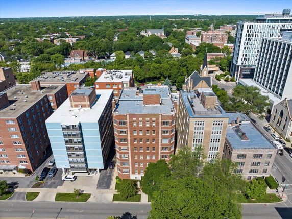 Aerial view of multiple mid-rise residential and commercial buildings with a green landscape in the background.
