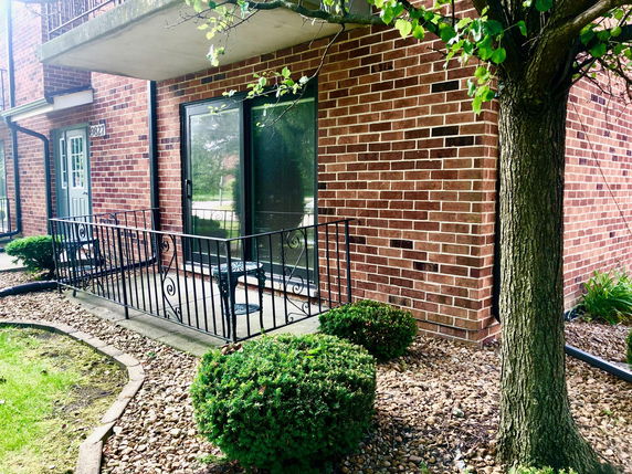 Front view of a brick building with a patio area and sliding glass door.