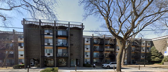 Front view of a multi-story apartment building with brick exterior and balconies.