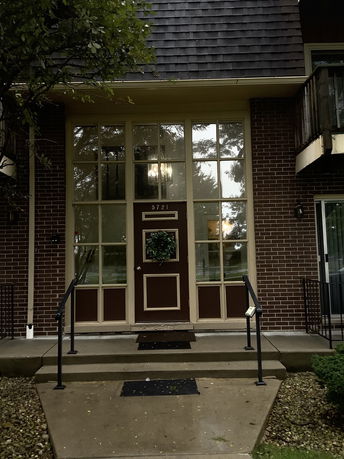 Front view of a building entrance with a brick facade and large glass windows.
