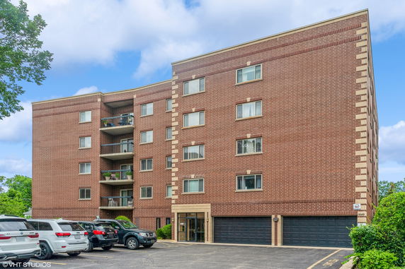 Front view of a multi-story brick apartment building with balconies.