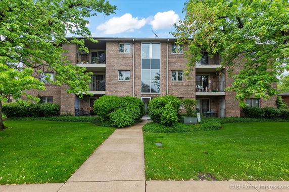 Front view of a three-story brick apartment building with balconies.