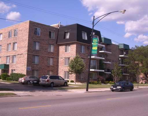 Front view of a multi-story brick apartment building with balconies.