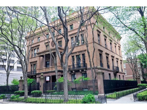 Front view of a large, three-story brick building with decorative architectural details.