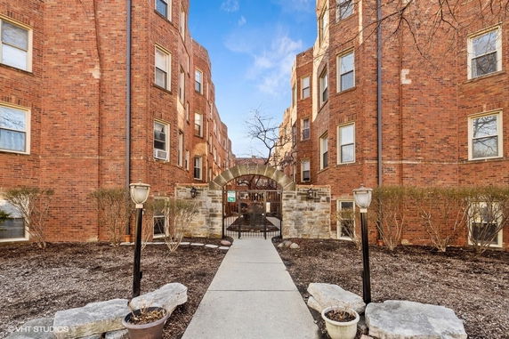 Front view of a brick apartment building with arched entrance.