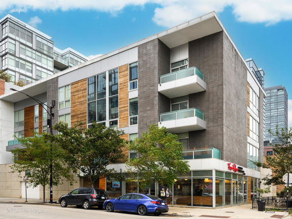 Front view of a modern multi-story building with balconies and large windows.