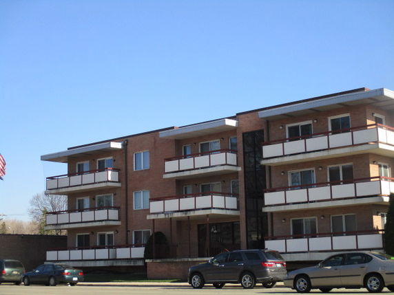 Front view of a multi-story brick apartment building with balconies.