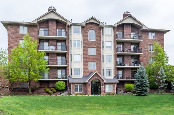 Front view of a multi-story brick apartment building with balconies.