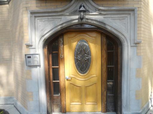 Front view of a building entrance with a wooden door and decorative glass panel.