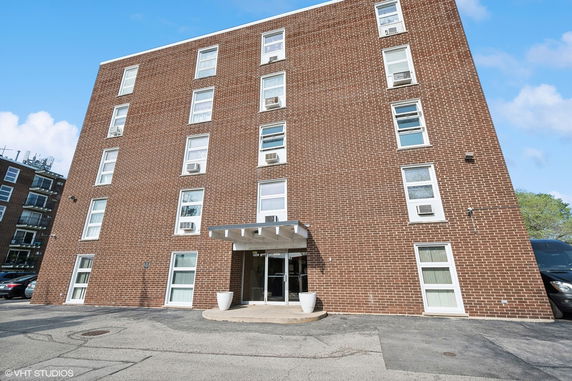 Front view of a multi-story brick building with multiple windows and a central entrance.