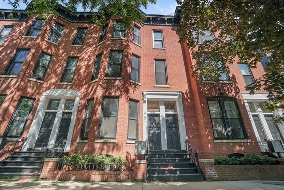 Front view of a multi-story brick townhouse with multiple entryways.
