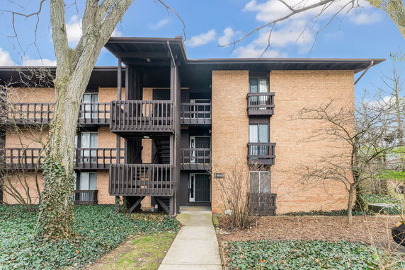 Front view of a multi-story brick apartment building with balconies.