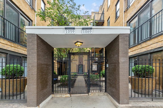 Front view of a multi-story residential building entrance with a gated archway.