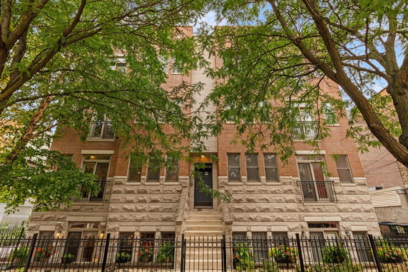 Front view of a multi-story brick building with stairs leading to the entrance.