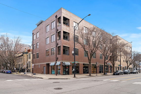 Front view of a multi-story brick building on a street corner.