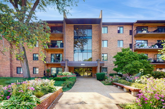 Front view of a multi-story brick apartment building with balconies.
