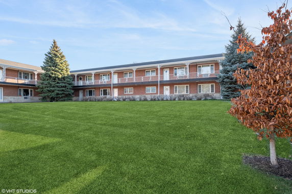 Front view of a two-story building with balconies and a well-maintained lawn.