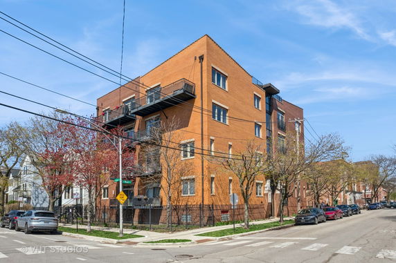Front view of a multi-story brick building with balconies on the street corner.