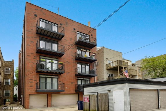 Front view of a multi-story brick apartment building with balconies.