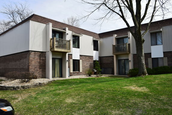 Front view of a multi-unit apartment building with brick and panel siding and small balconies.