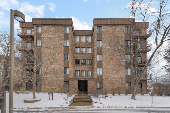 Front view of a multi-story brick apartment building with balconies.