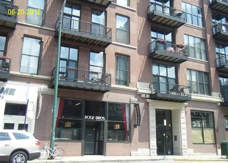 Front view of a multi-story building with balconies and a storefront.