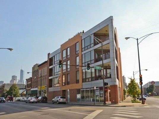 Front view of a multi-story apartment building on a city street corner.