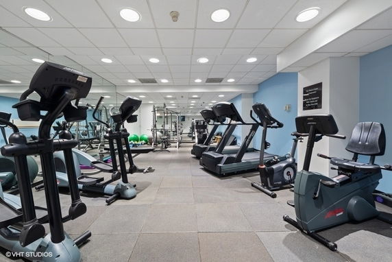 Room with gym equipment including treadmills and exercise bikes.