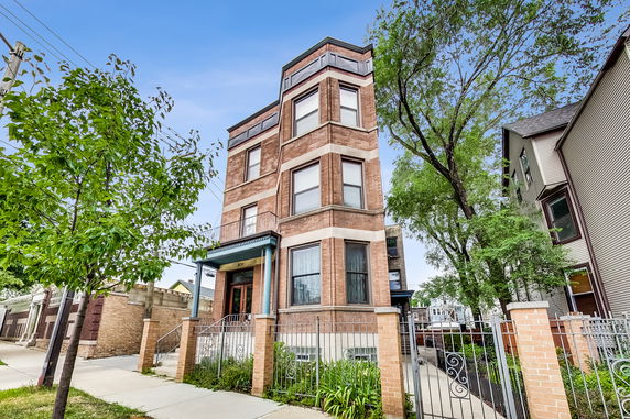 Front view of a three-story brick building with a gated entrance.