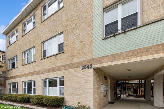 Front view of a multi-story brick building with multiple windows and an entrance area.