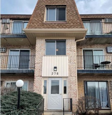 Front view of a multi-story building with balconies and a shingle roof.