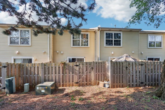 Rear view of a two-story residential building with a fenced backyard.
