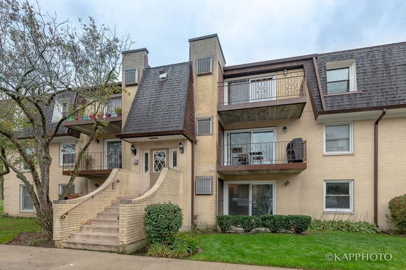 Front view of a multi-story residential building with balconies and a central staircase.